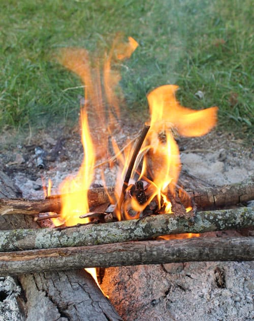 campfire started with a pinecone dipped in wax