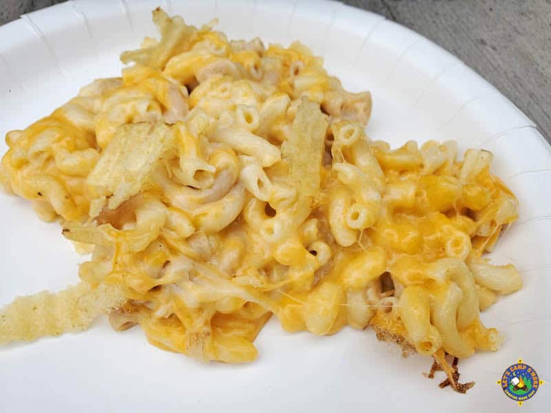 close up of a serving of macaroni and cheese on a white paper plate