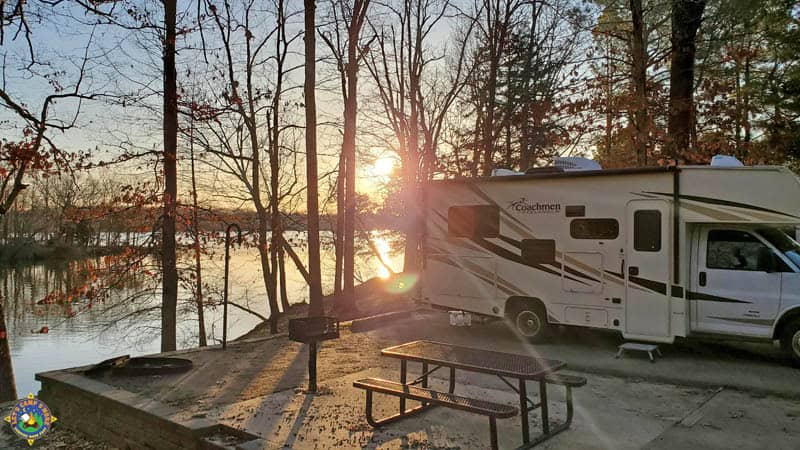 sunrise over a lake with a motorhome parked at a campground