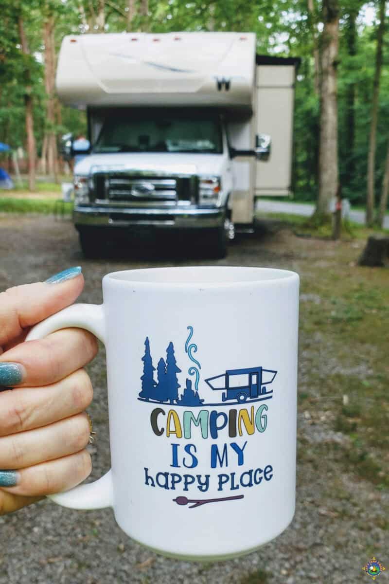 mug that says Camping is my Happy Place being held in front of a motorhome
