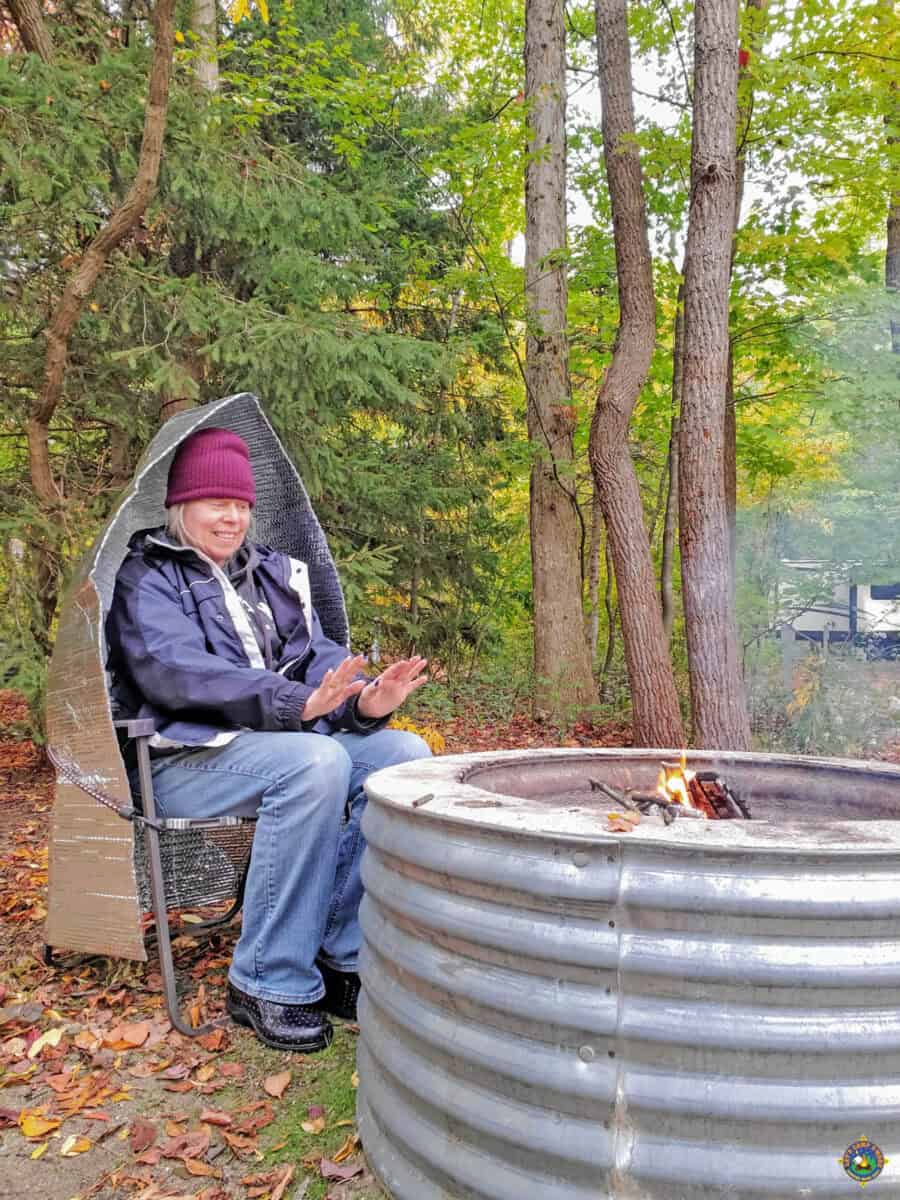 woman warming hands in front of a campfire with a reflector