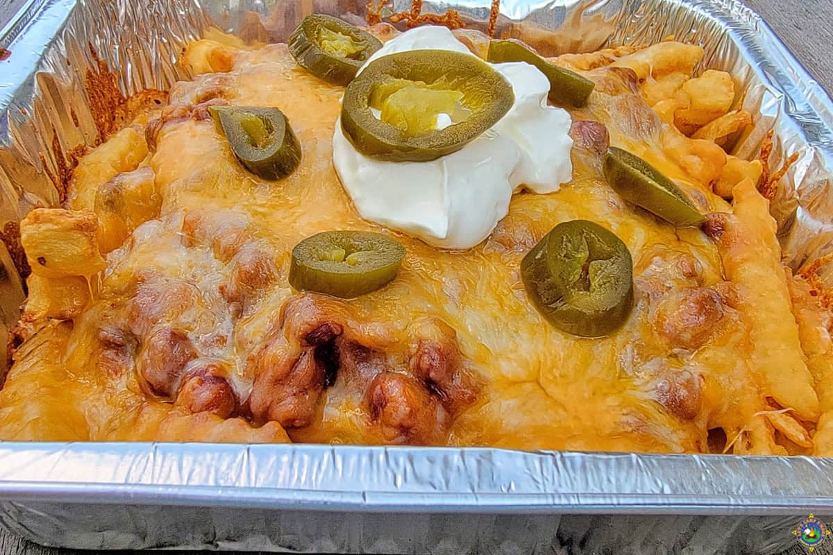 Grilled French Fries with cheese chili sour cream and jalapeno in a foil pan