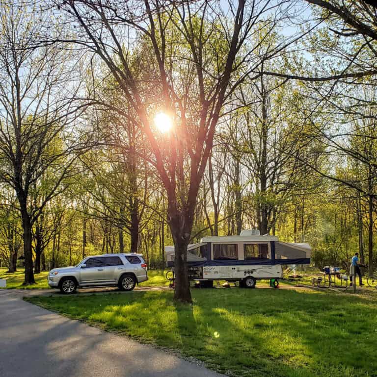 Pop Up Camper in a Campground with the sun coming through the trees