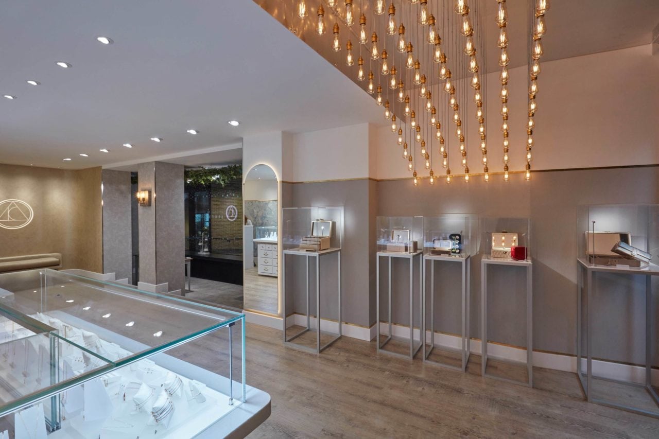 Several glass jewelry displays with gold lamps on the ceiling.