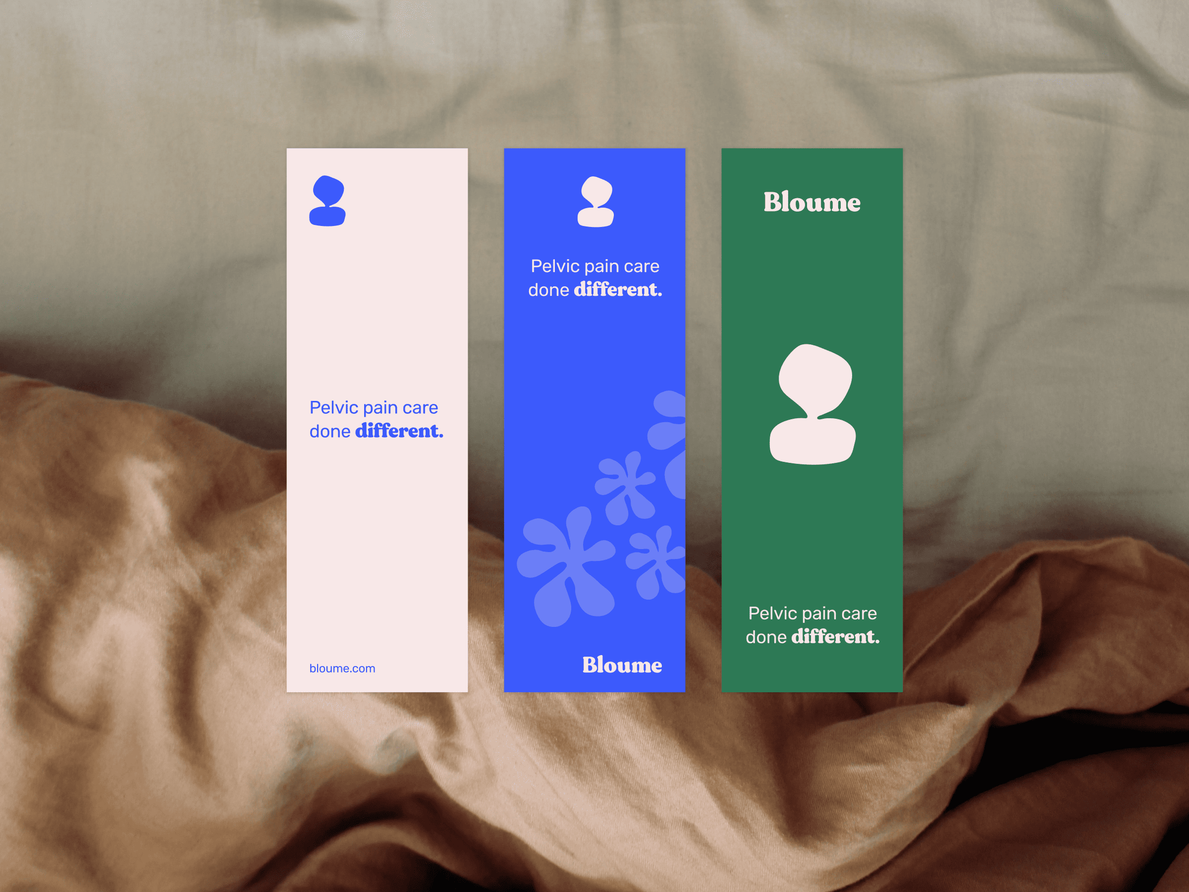 Three vertical banners on beige fabric. First banner: pink with the text Pelvic pain care done different and the word Bloume. Second banner: blue with flowers, featuring the same text and Bloume. Third banner: green with identical phrase and Bloume.