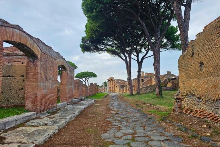Pathway through Roman ruins at Ostia Antica with iconic pine trees in the background.