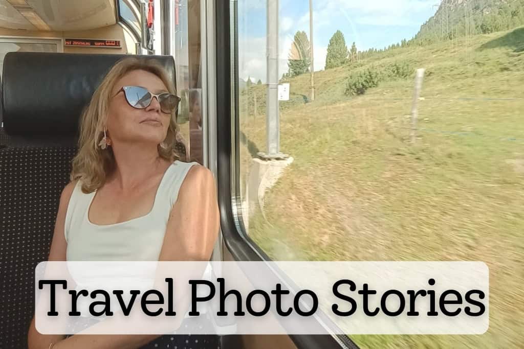 Maria Dol of Map And Camera enjoying a scenic train ride, gazing out the window at lush green hills, capturing the essence of storytelling through travel photography.