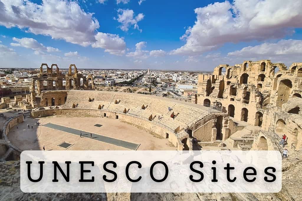 Panoramic view of the ancient Roman amphitheater in El Jem, Tunisia, a well-preserved UNESCO World Heritage Site, with the surrounding town and blue sky in the background.
