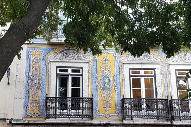 Intricately decorated azulejo façade on a historic Lisbon building, featuring ornate blue and yellow tiles—an unassuming architectural treasure among the city’s hidden gems.