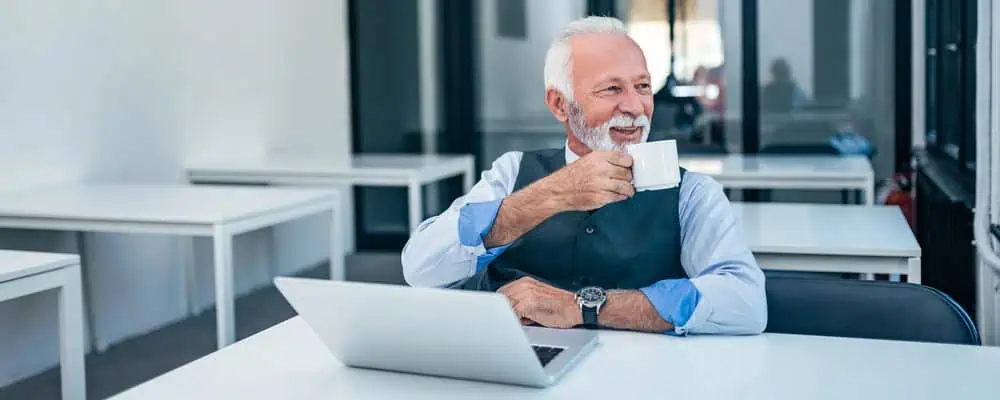 Older entrepreneurs drinking coffee while sitting in front of a laptop