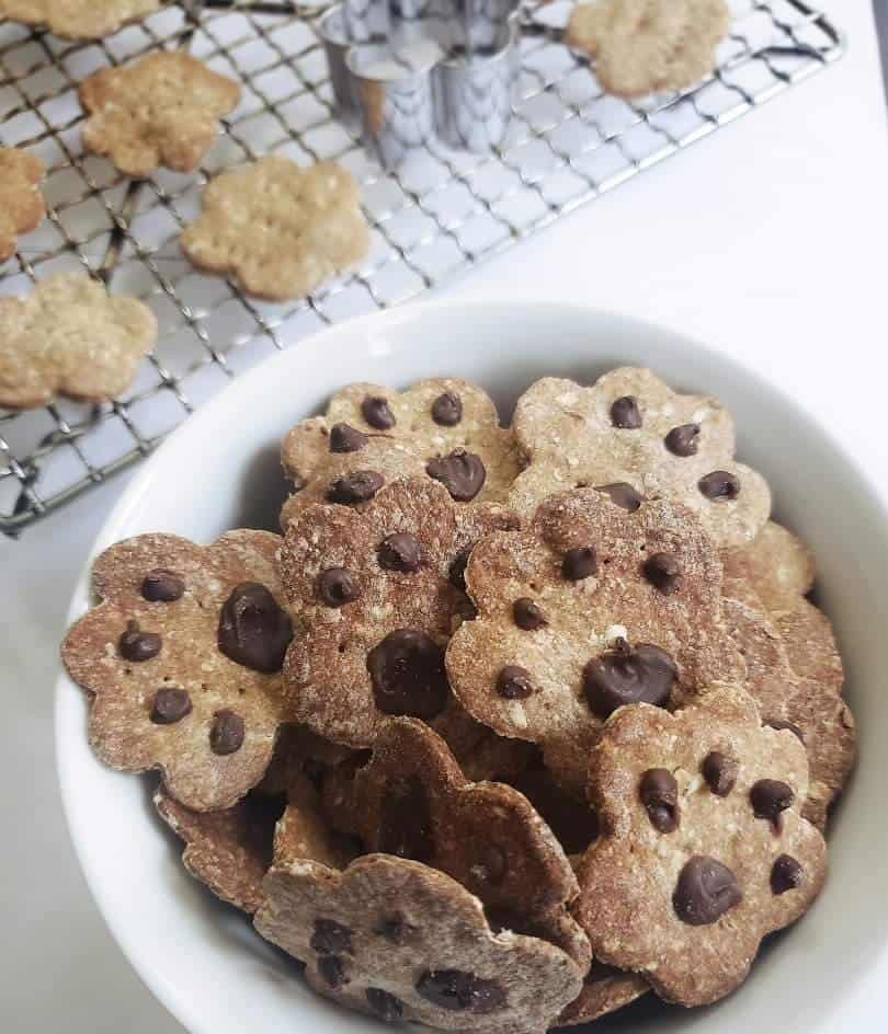 A white bowl filled with baked dog cookies shaped like paws.