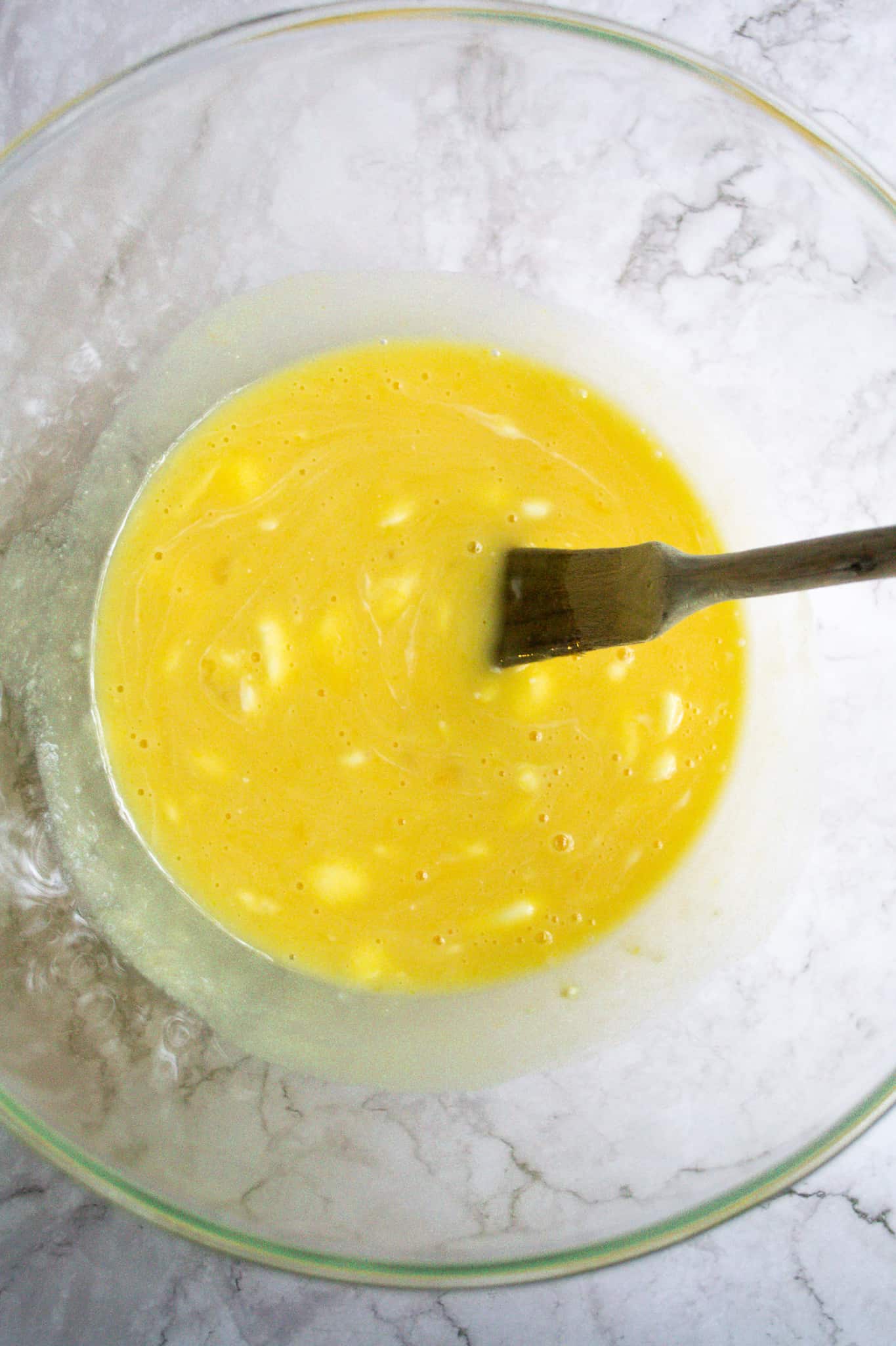 Bread batter wet ingredients all mixed together in a glass bowl.