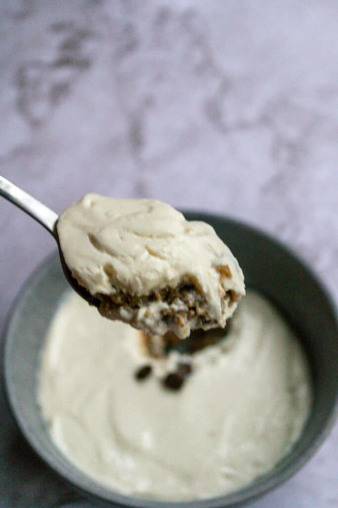 A bite of overnight weetabix on a spoon with a bowl of it in the background. 
