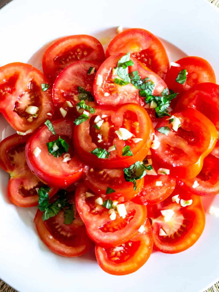Top view of tomato salad on a white plate.