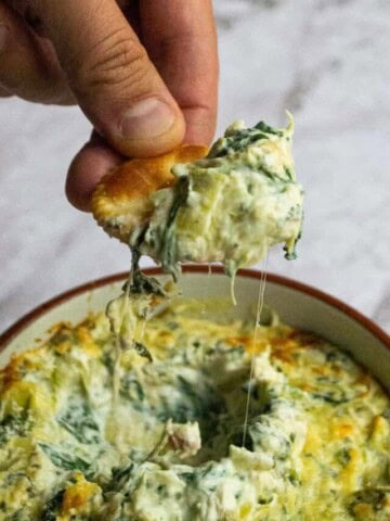 Healthy spinach artichoke dip on a cracker.