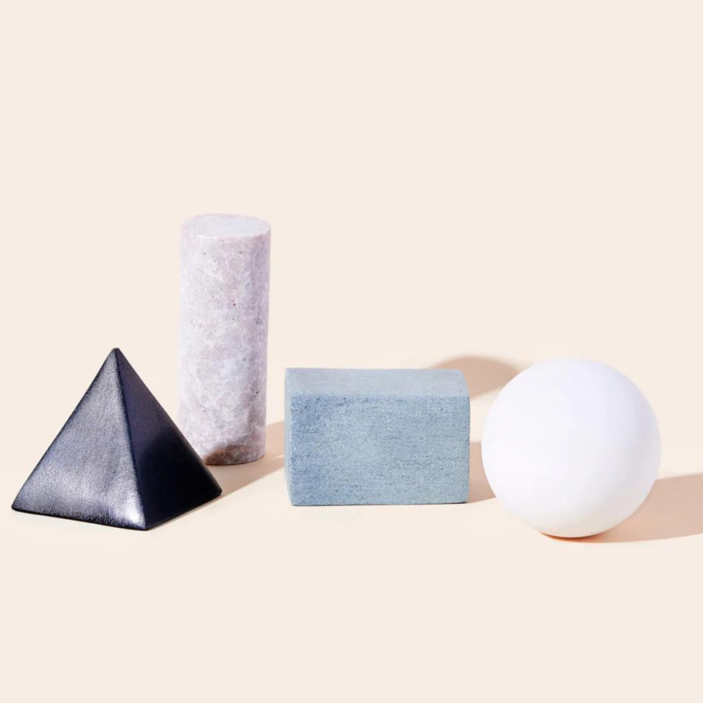 Four whisky stones of various shapes against a peach-coloured background.