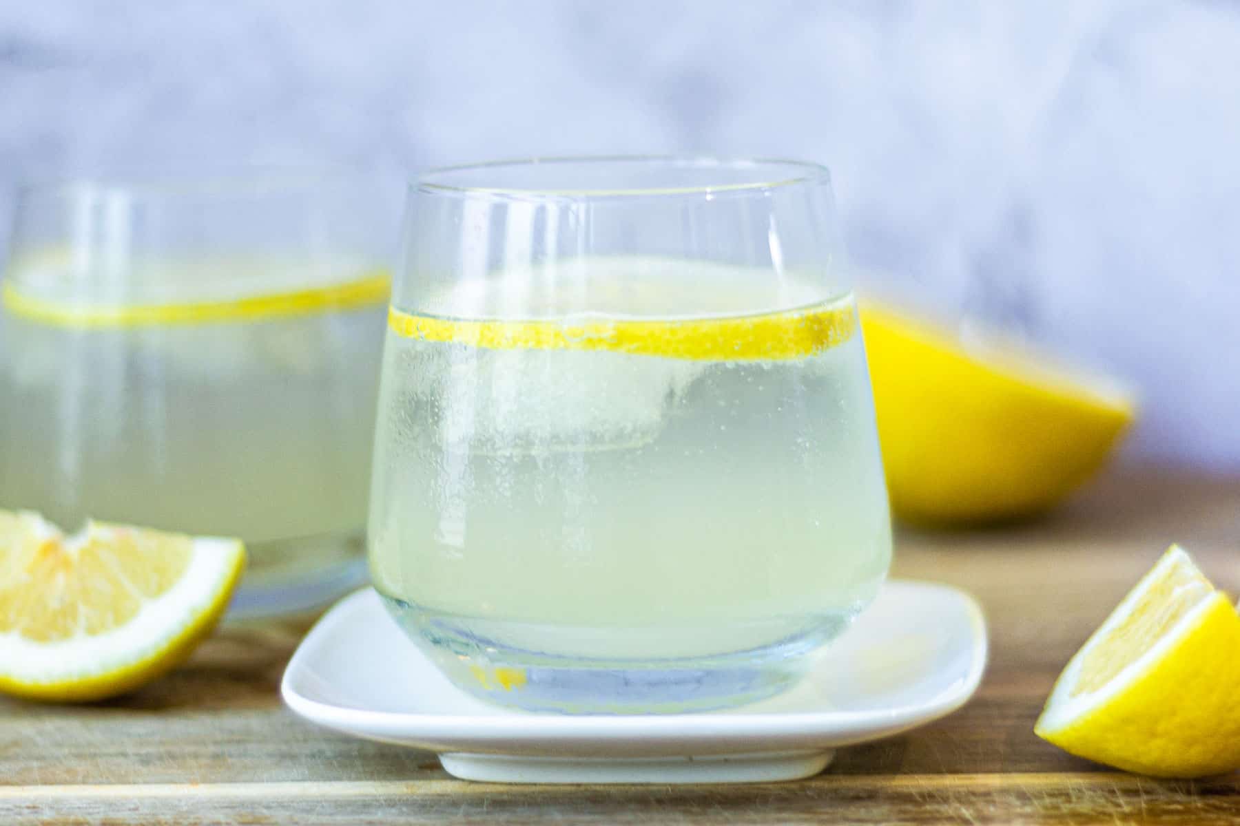 Limoncello Spritz with lemons next to it and a marble background.