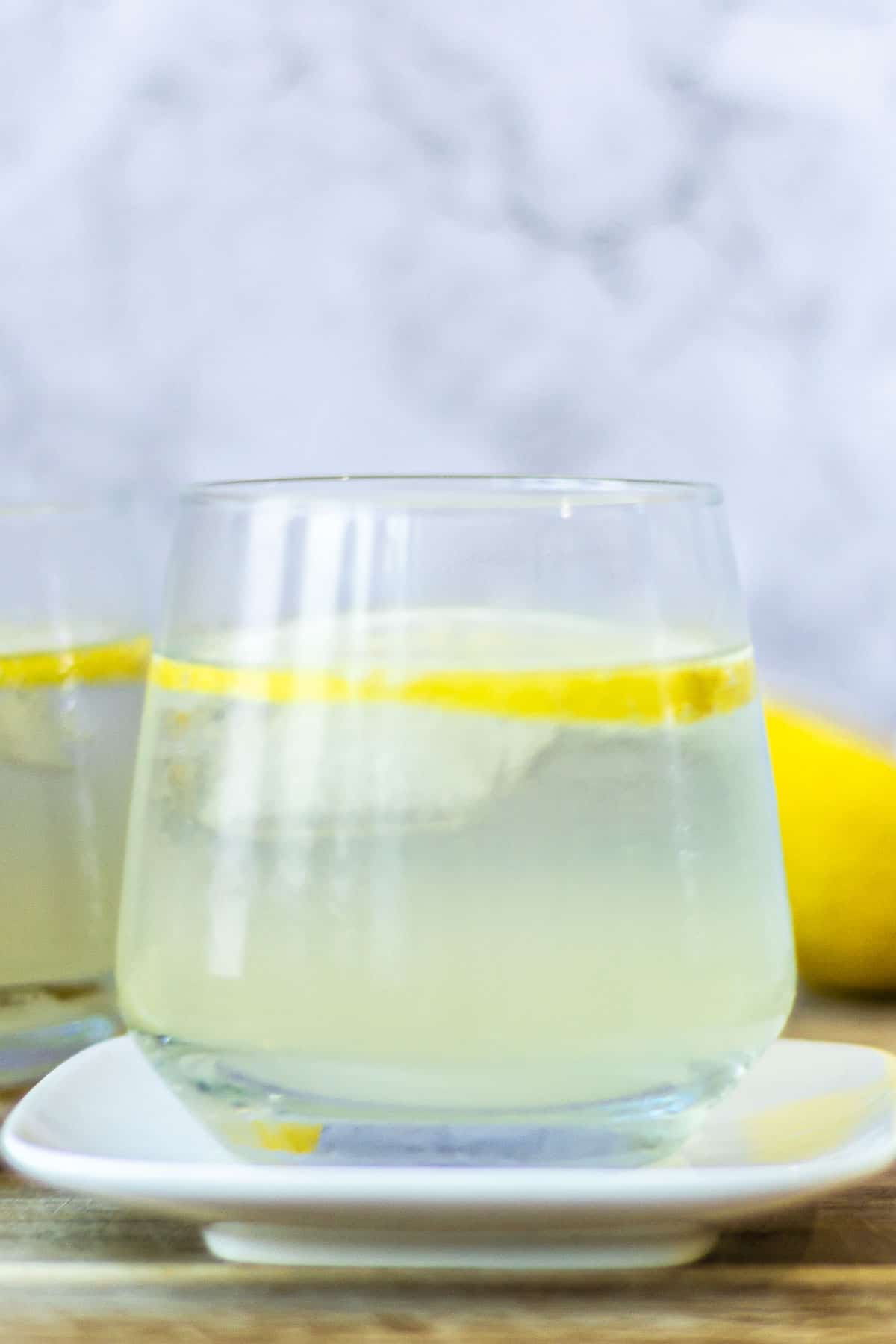 Close up of a Limoncello Spritz with lemons next to it and a marble background.