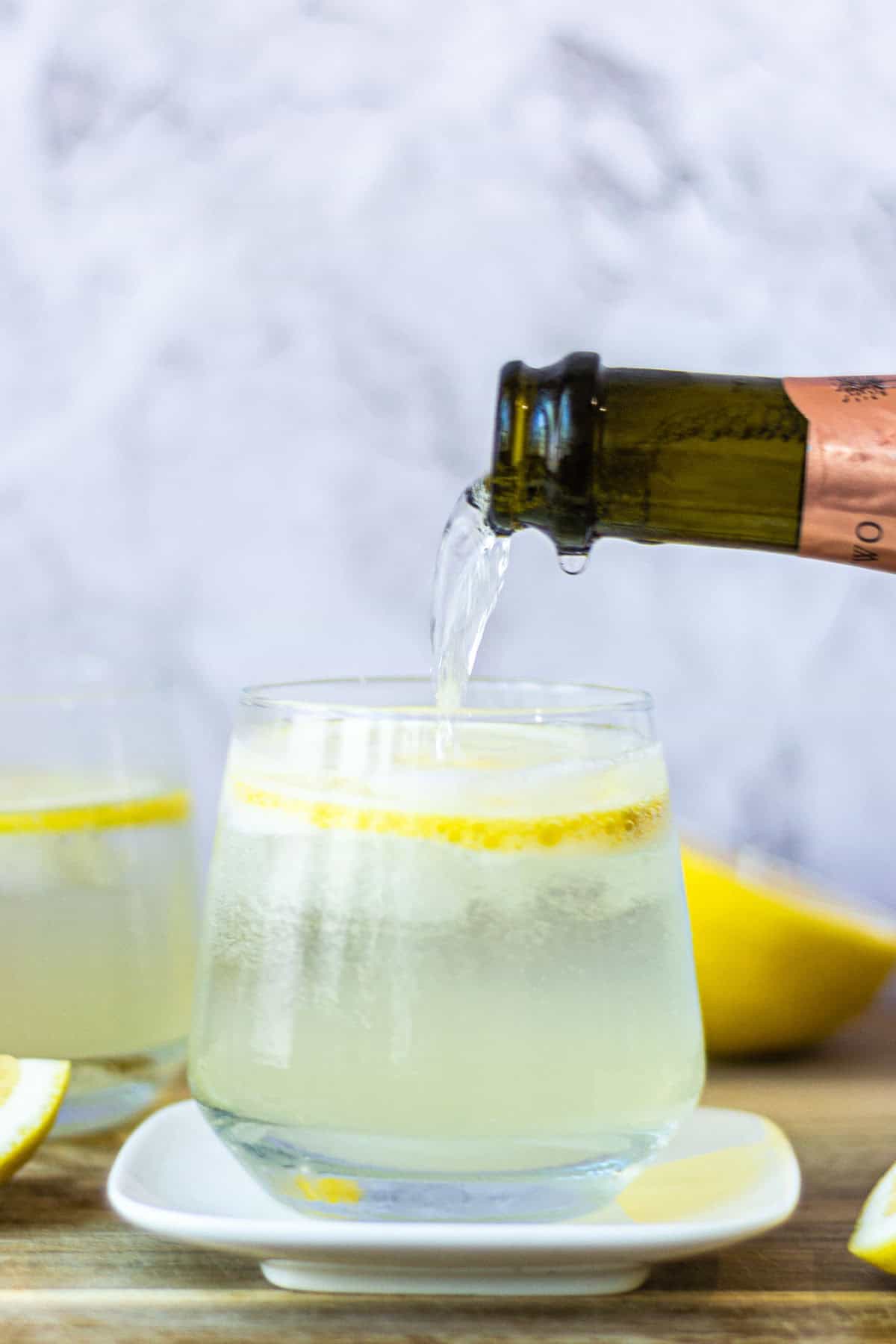 A bottle of Prosecco topping up a Limoncello Spritz.