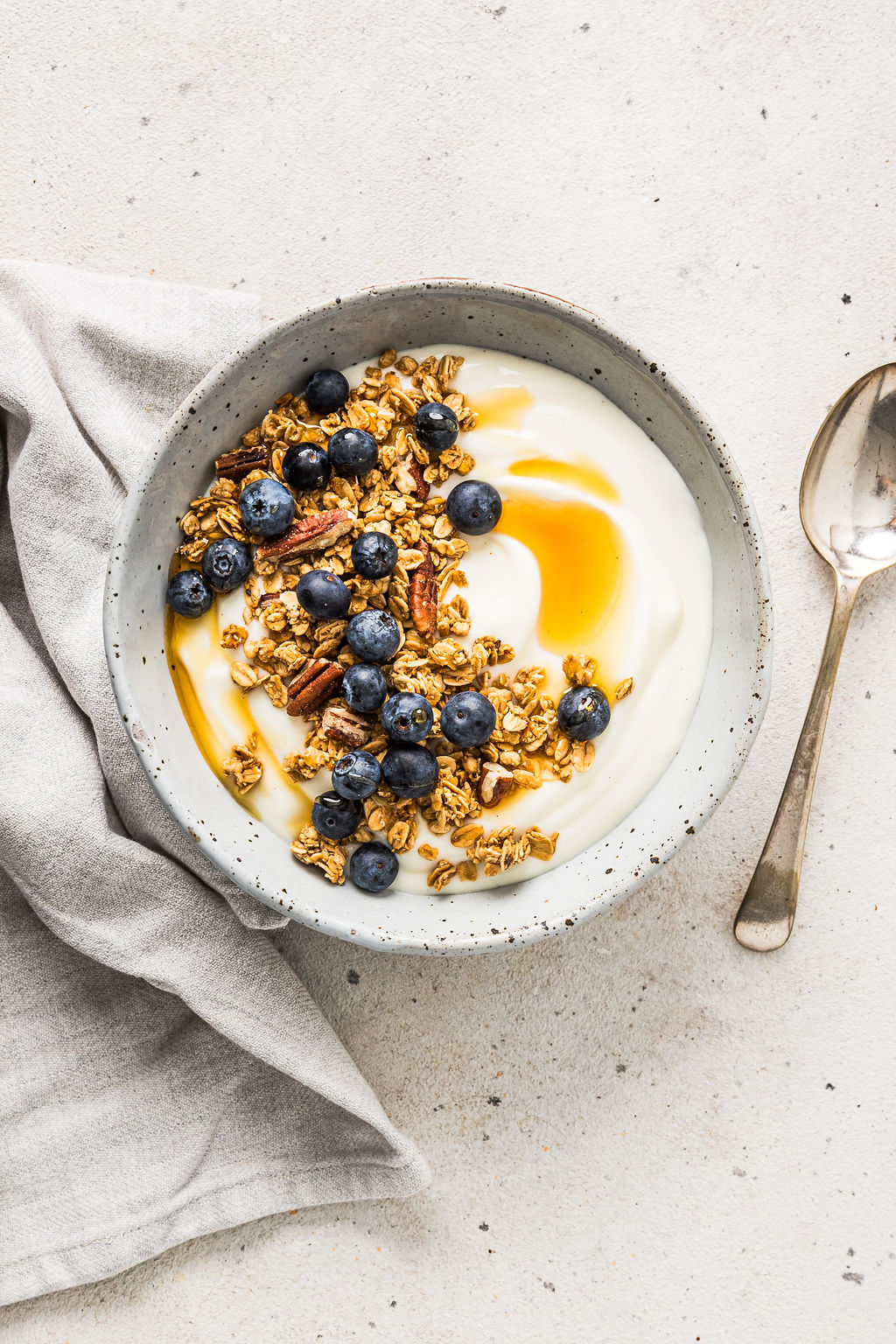 Overhead view of vegan soy yoghurt with granola, honey and blueberries on top.