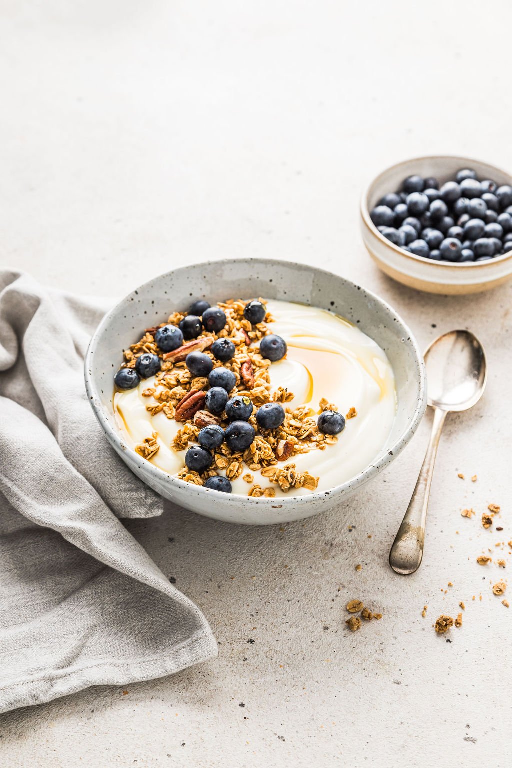 front view of vegan soy yogurt in a grey bowl, topped with blueberries and granola.