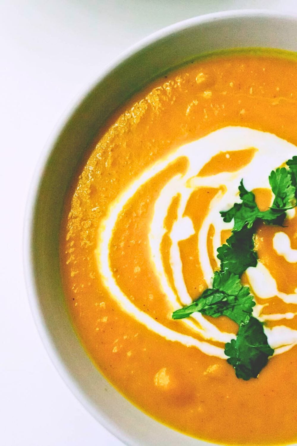 Overhead view of pumpkin soup coconut milk and coriander on top.
