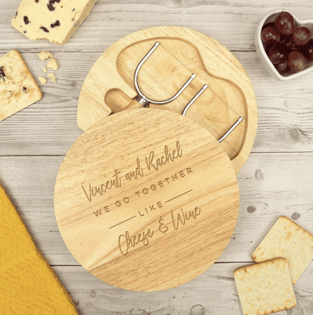 Overhead view of a custom charcuterie board with the quote 'Vincent and Rachel, we go together like cheese & wine'.
