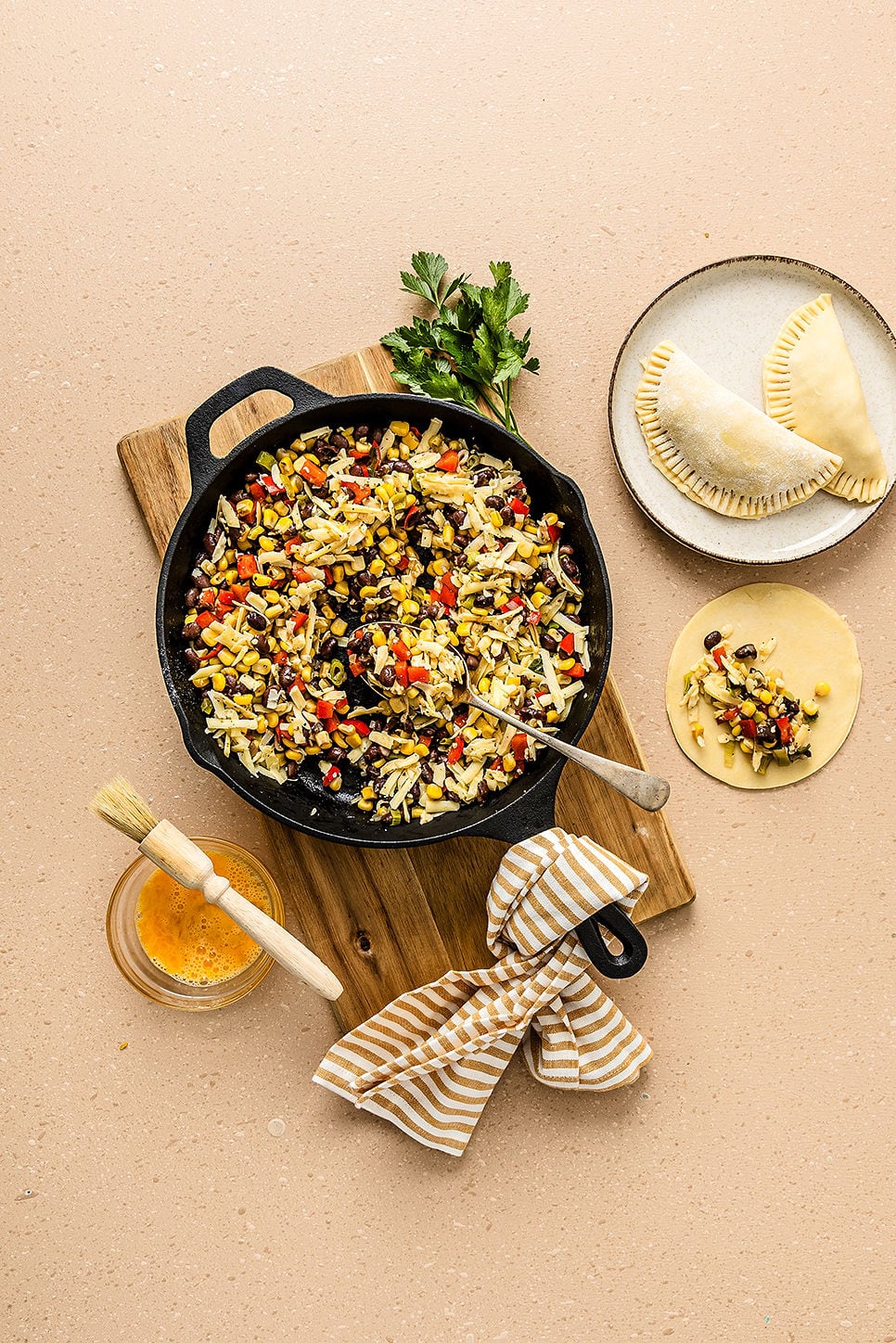 Overhead view of ingredients to make vegetarian empanadas, including a pan of filling and raw dough.