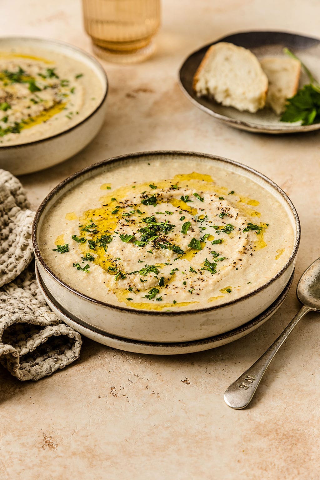 Front view of creamy cauliflower soup with a drizzle of olive oil and some parsley leaves on top.