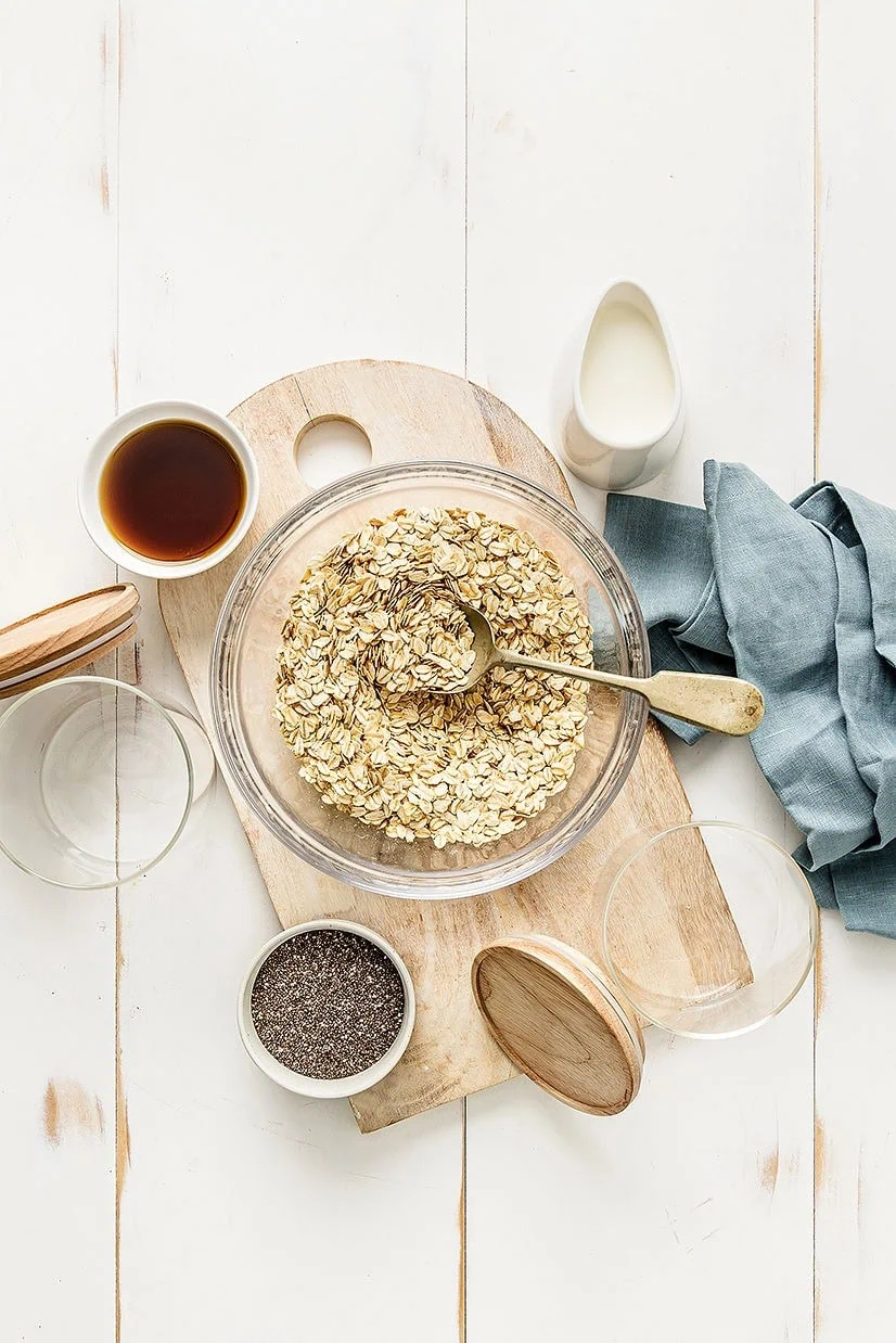 Overhead shot showing the ingredients for meal prep overnight oats including oats, chia seeds, soy milk and maple syrup.