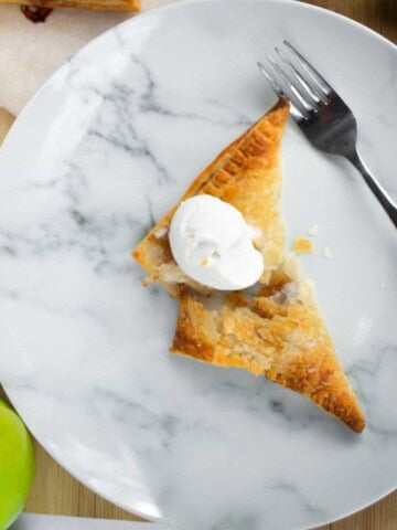 Closeup of a vegan apple turnover with a scoop of vanilla ice cream.