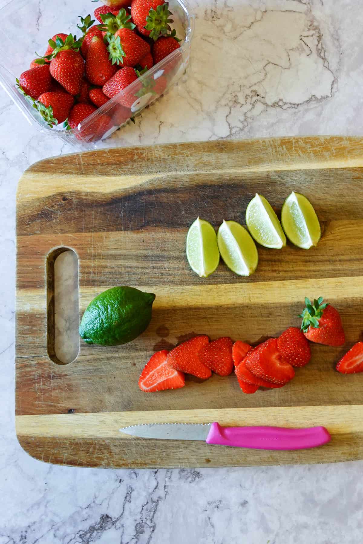 Overhead shot showing a cutting board with strawberries and limes.