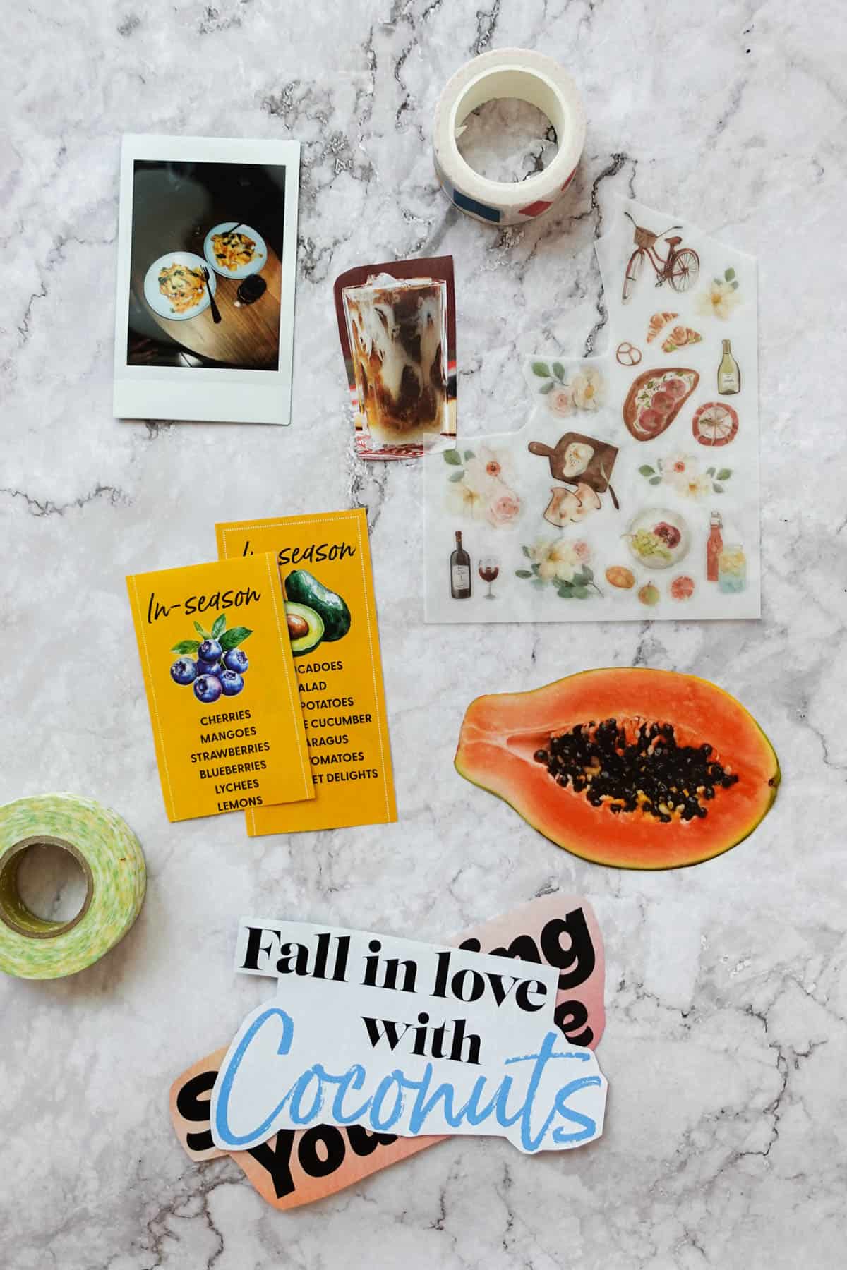 Overhead shot of scrapbook materials for a cooking journal including a photo, magazine cutouts, stickers and washi tape.