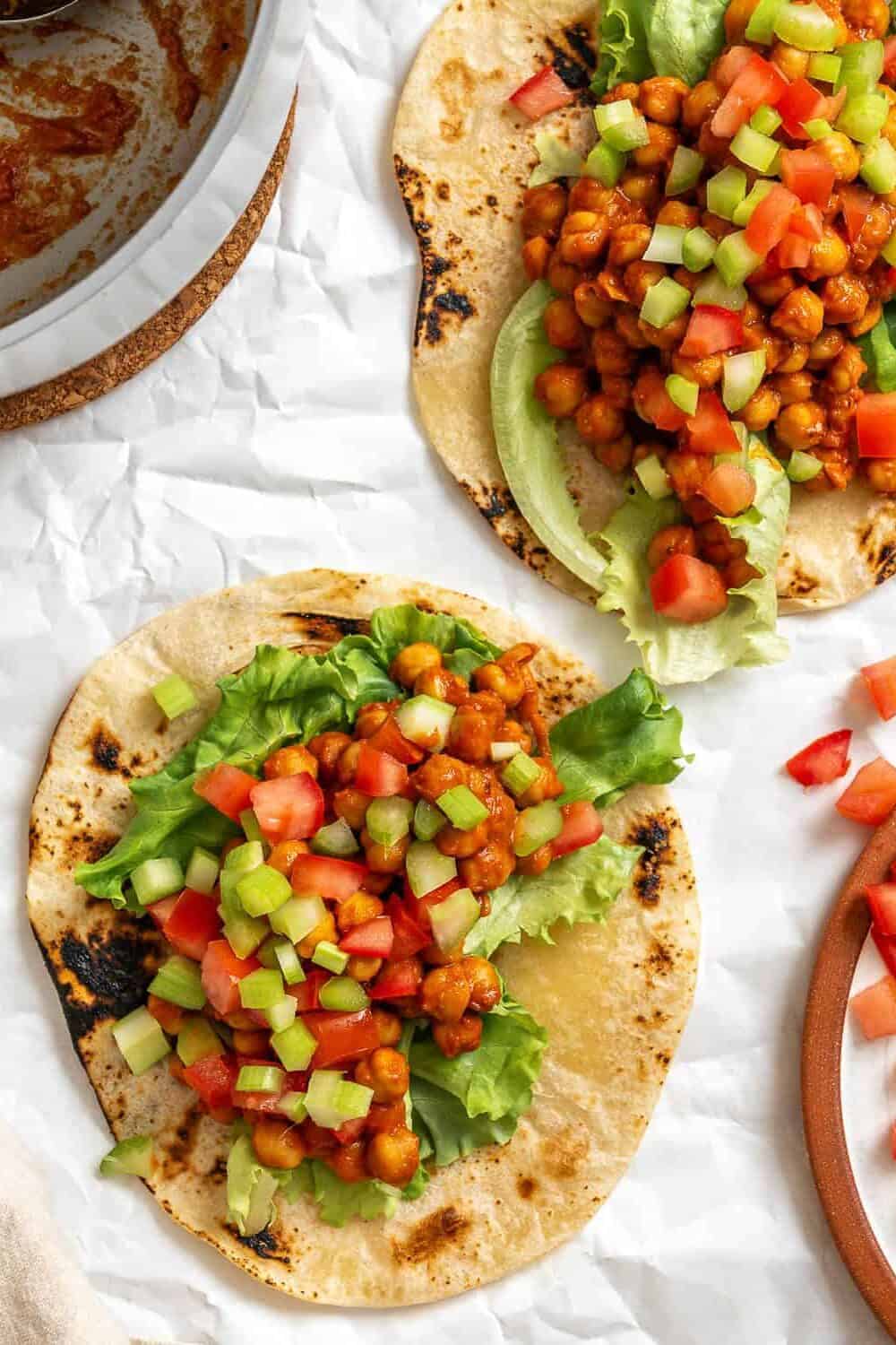 Overhead shot of barbecue chickpeas on tortilla warps with lettuce, tomato and cucumber.