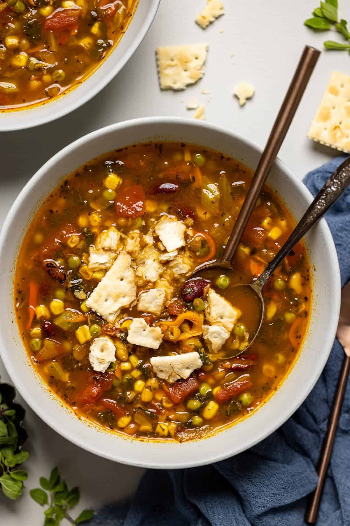 Overhead shot of loaded veggie soup with peas, corn and beans with crushed crackers on top.