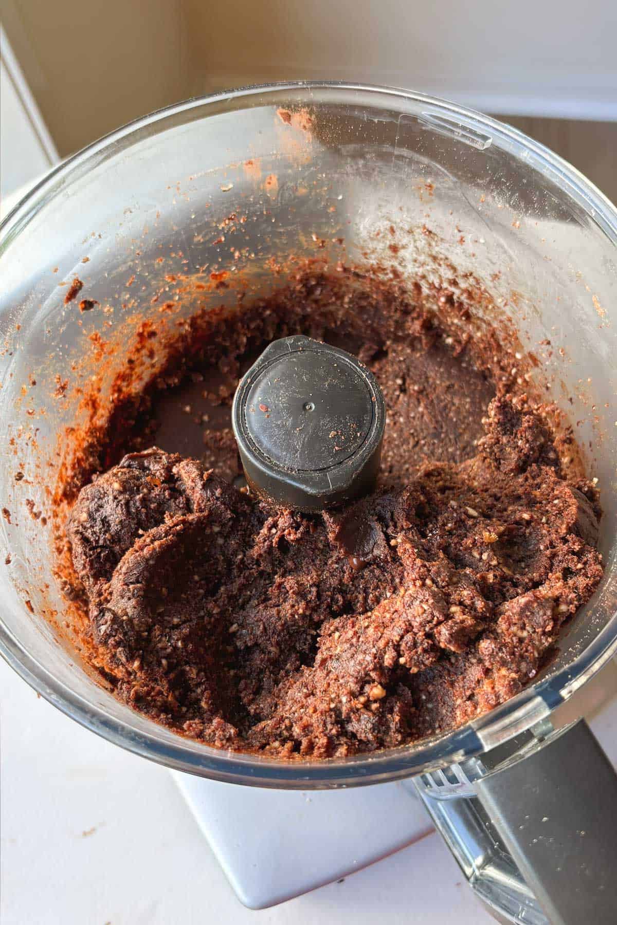 Overhead shot of food processor contents (including dates, almond meal, and protein powder) while protein balls are being made.