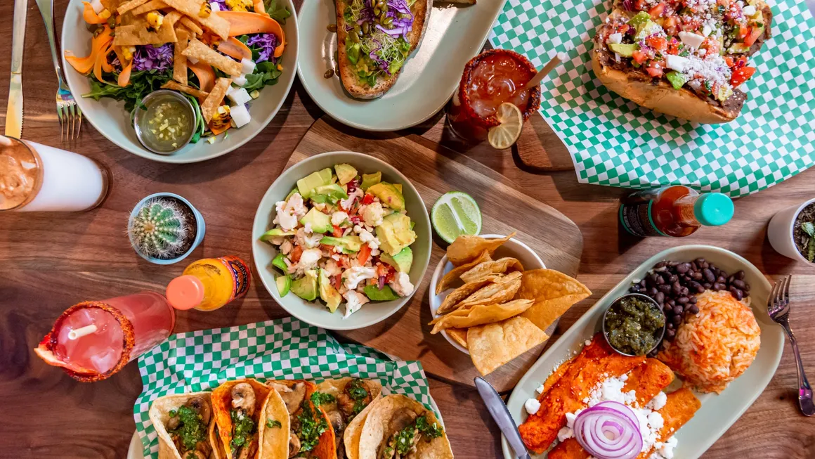 Overhead view of food on the table at Penelope’s Vegan Taqueria Andersonville with chips, rice, tacos and drinks on a wooden table.
