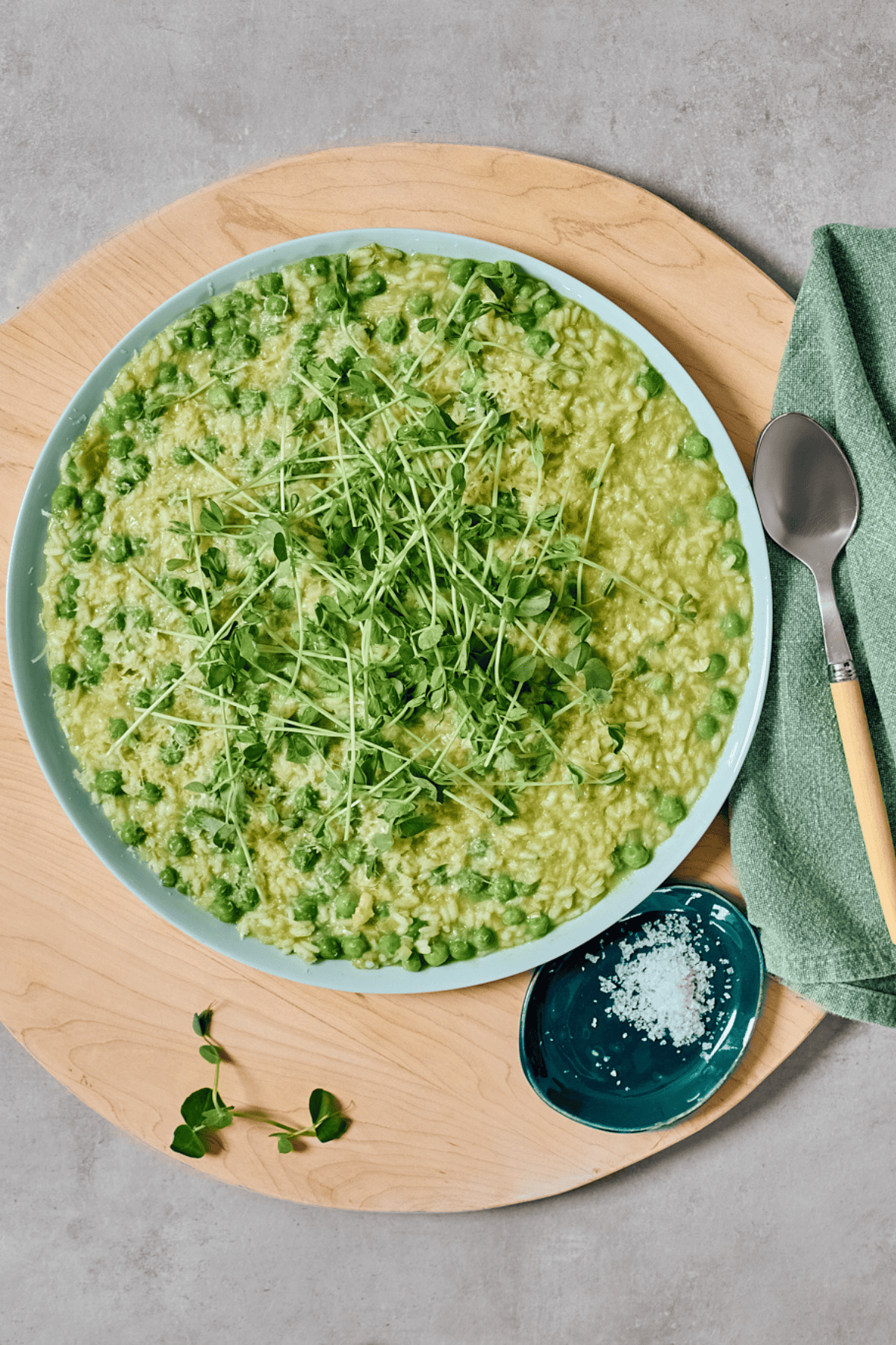 Overhead shot of pea and leek risotto in a bowl, topped with pea tendrils.