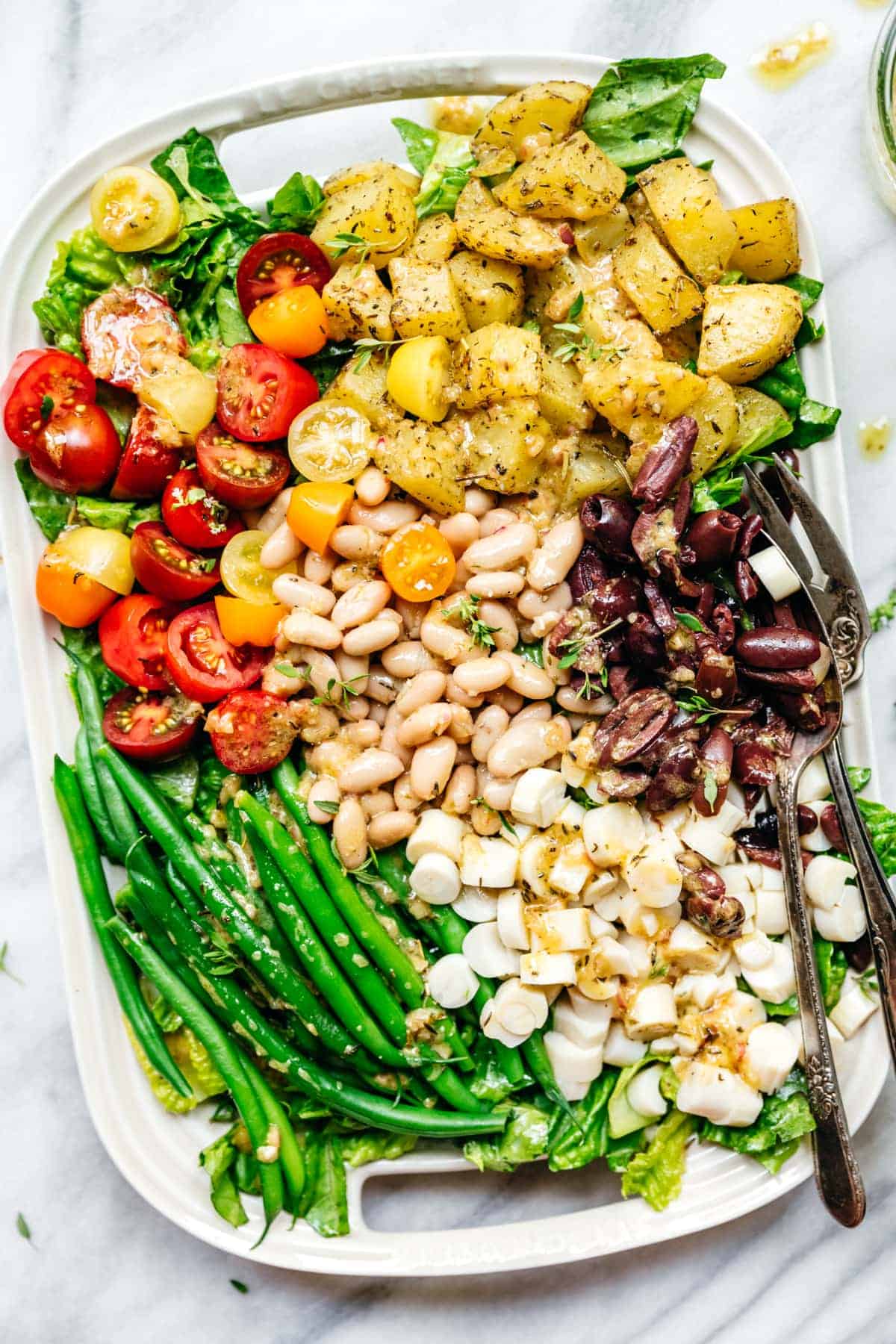 Overhead shot of a vegan nicoise salad on a large, white serving platter.