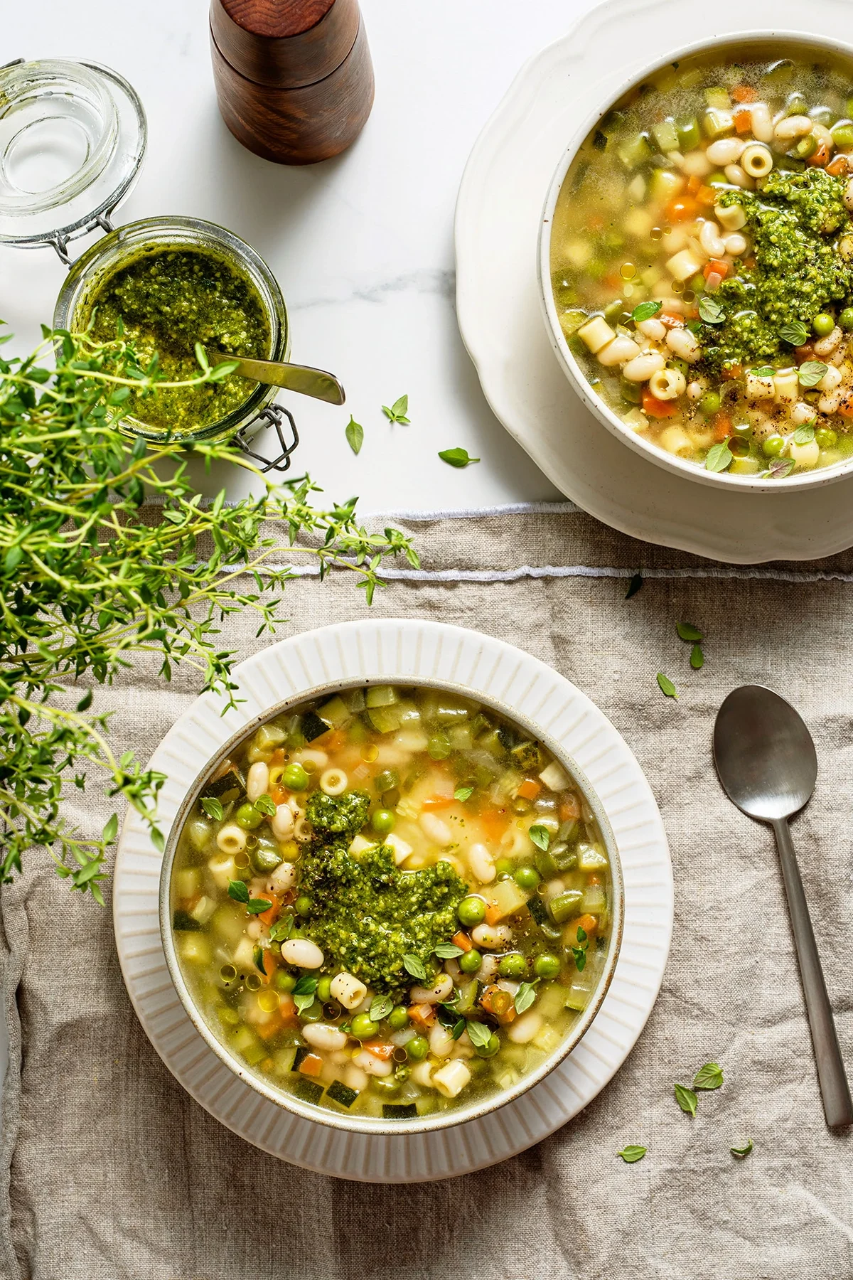 Overhead shot of two bowls of soupe au pistou on a white table.