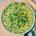 Overhead shot of pea and leek risotto in a bowl, topped with pea tendrils.