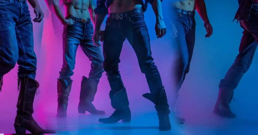 men dancing with tight abs, genes, and country boots with blue and purple faded background, male revues