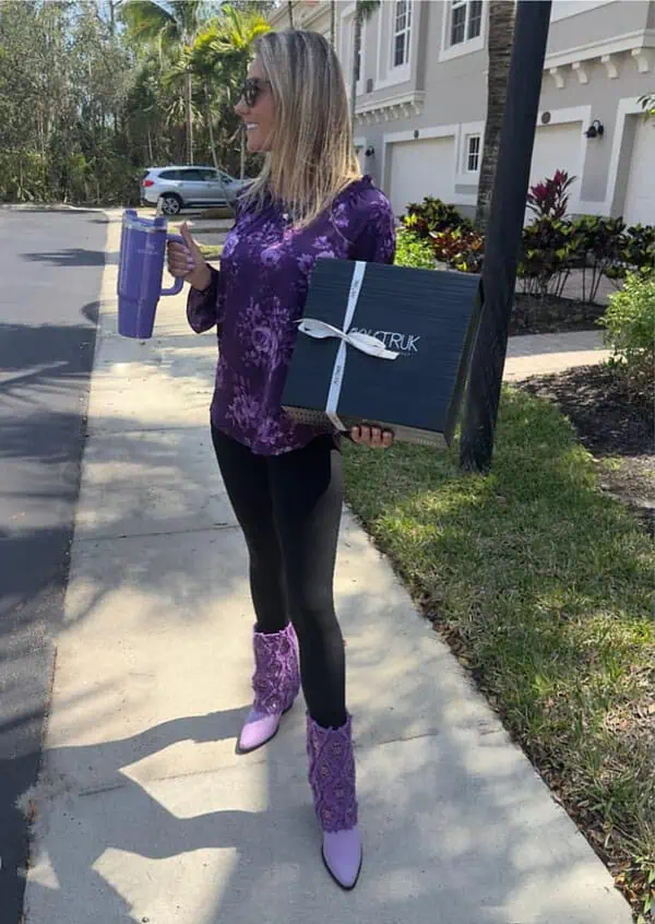 woman hold jug, and SkyStruk Shoe Box, wearing Gram Glam Purple Boots with cuff, fringe, crystal diamonds.