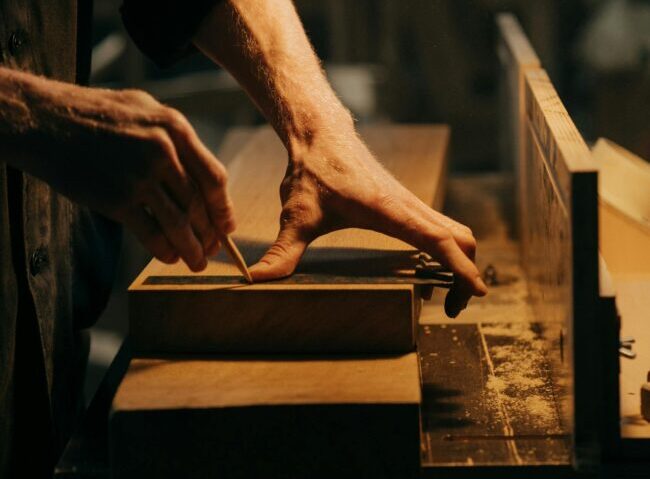 A craftsman skillfully sanding a wooden plank in a well-lit workshop.