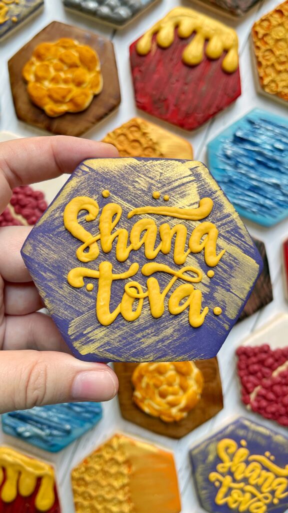 hexagon decorated with royal icing lettering that says shana tova