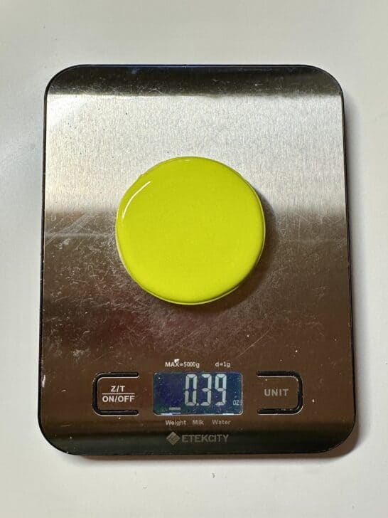 image of cookie flooded on a piece of paper on top of a food scale to measure royal icing amount