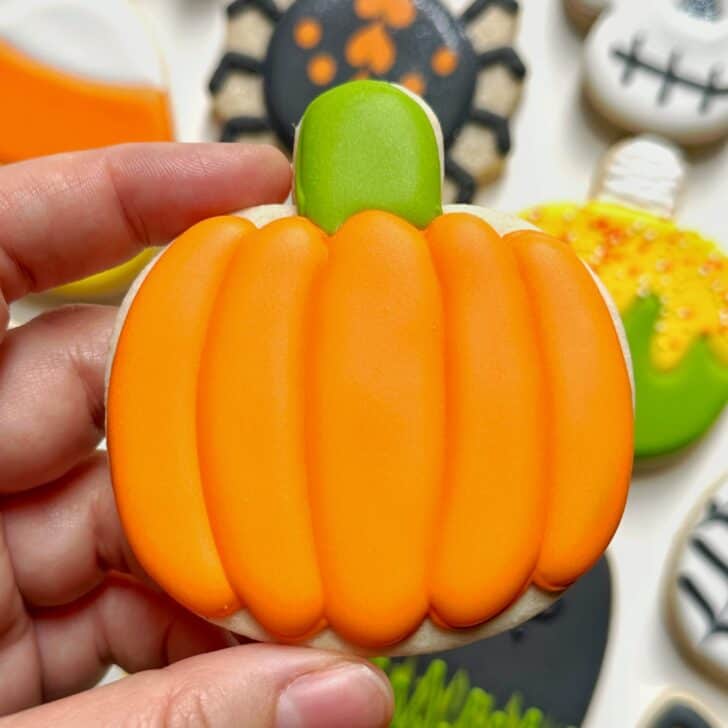 photo of pumpkin halloween cookie decorated with royal icing