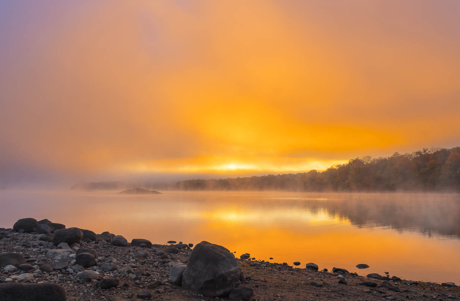 A beautiful orange-colored sunrise on the shore of Indian Lake in the Adirondack Mountains.
