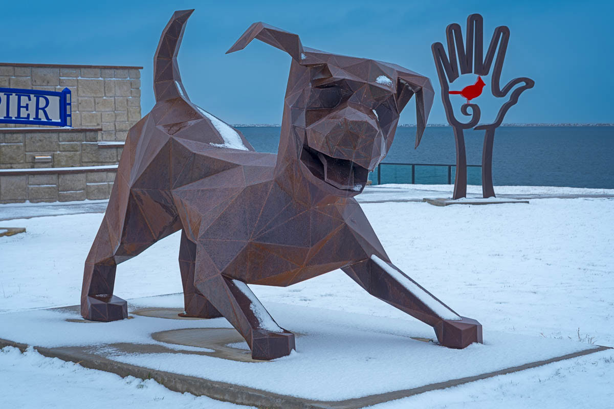 Metal sculptures of a playful dog and a bird-in-a-hand that are found at William S. Cahill Pier in Oswego, New York