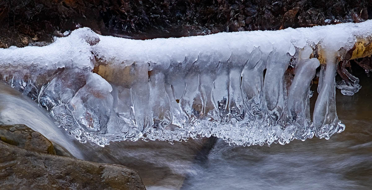 Ice that has accumulated on a stick across a small waterfall and eroded by the water.